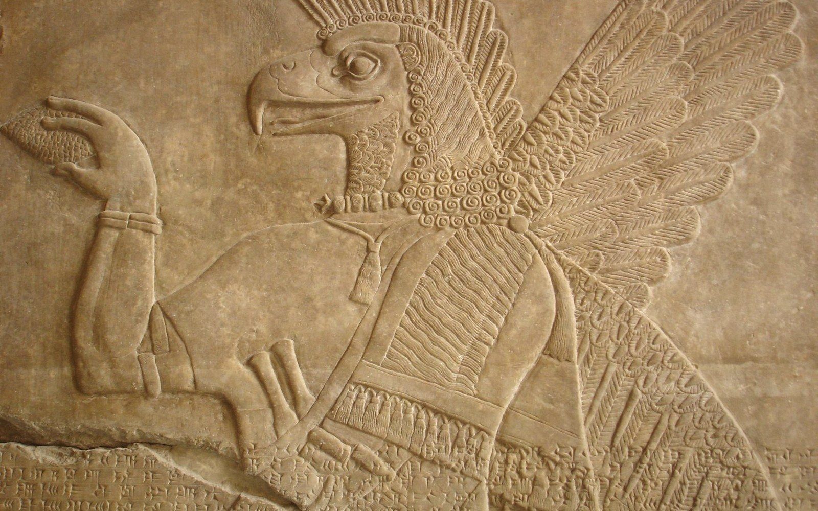 Carved stone relief of an eagle-headed winged figure with cuneiform inscription below