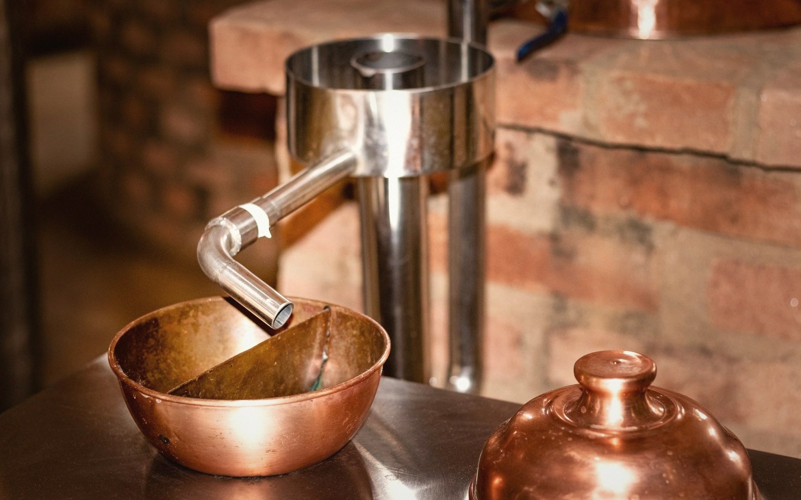 Steam rising from an open mash tun, copper vessel against a dark stone wall, no figures visible